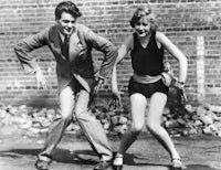 a man and woman are dancing in front of a brick wall